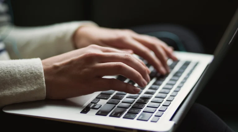 woman typing on an Apple MacBook